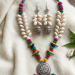 Handmade Kori Jewellery Set featuring natural shell accents, colorful thread beads, hand-painted parrot motifs, oxidised silver pendant, and matching jhumka earrings for Durga Puja and ethnic fashion.